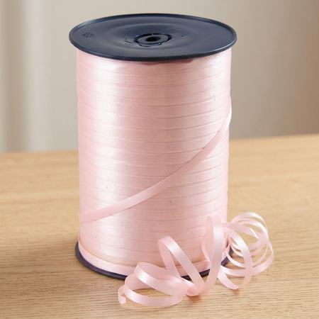 Pale pink curling ribbon reel close up on a wooden table with a neutral background, in square format