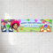 Personalised birthday banner on a white brick wall with soft light and shade, in square format
