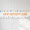 Personalised Happy Birthday Laura banner on a white brick wall with soft light and shade, in square format