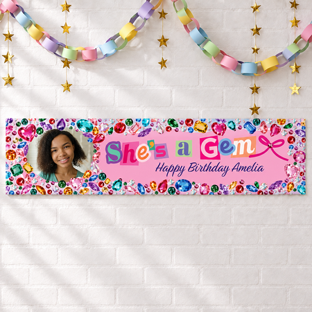 Personalised She's a Gem banner on a white brick wall with pastel paper chains and gold stars