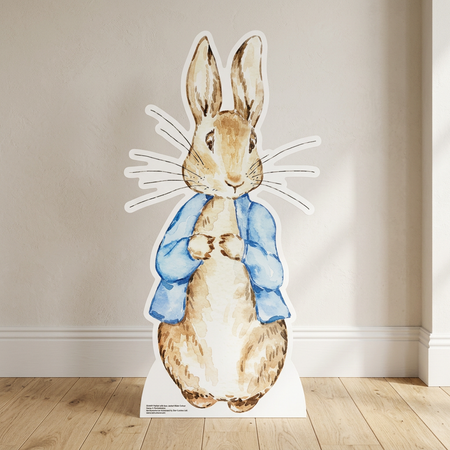 Peter Rabbit cardboard cutout on a wooden floor against a neutral wall with soft light and shade, in square format
