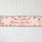 Pink floral banner on a white brick wall with soft light and shade, in square format