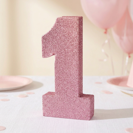 Pink glitter number 1 decoration on a white tablecloth with soft pale pink first-birthday styling