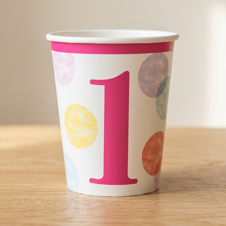 Pink number 1 birthday cup on a wood table with a neutral background and soft light and shade, square format