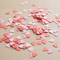 Pink paper heart confetti scattered on a wooden table in square format