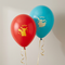 Red and blue Pokémon balloons floating with gold curling ribbons against a softly lit neutral wall, in square format