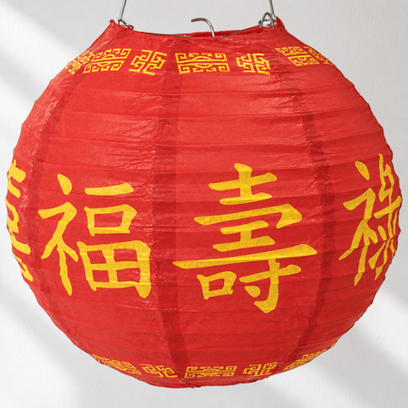 Red Chinese paper lantern hanging against a white wall with light and shade, square format
