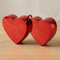 Red double-heart decoration close up on a wooden table with a softly lit neutral background, in square format