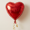 Red heart foil balloon with the Anagram logo removed, retaining the gold ribbon and neutral background