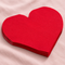 Red heart-shaped paper napkins close up on a pale pink tablecloth with soft light and shade, in square format