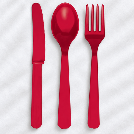 Red plastic cutlery set on a white tablecloth with light and shade, square format