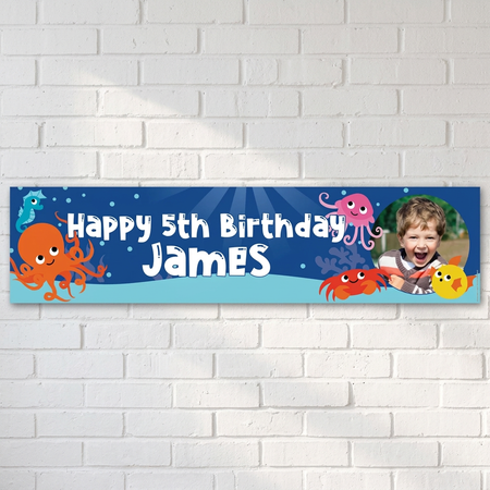 Sea-life birthday banner on a white brick wall with soft light and shade, in square format