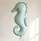 Seahorse balloon floating with silver curling ribbon against a neutral wall, in square format