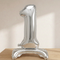 Silver number 1 balloon on a wooden table with soft neutral lighting and extra headroom