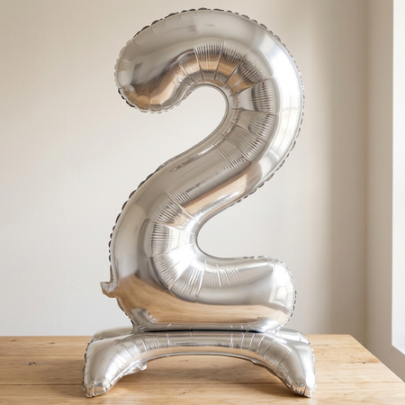 Silver number 2 standing balloon on a wooden table with a neutral background and natural light and shade, square close-up