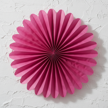Single Hot Pink Tissue Fan Close Up on White Textured Wall