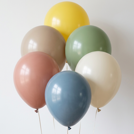 Six coloured latex balloons with realistic shapes and reflections against a softly lit white wall, in square format