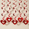 Square close-up of five red hanging swirl hearts against an off-white wall with soft light and shade