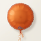 Square close-up of the orange foil balloon floating with matching curling ribbon against a softly lit neutral background