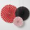Square close-up of the three paper fans against a white wall, with soft light and shade and strings extending off the top edge