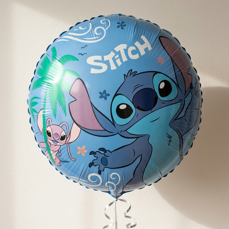 Stitch balloon floating with silver curling ribbon against a neutral wall with soft light and shade, close up in square format