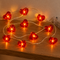 Ten red wire heart lights glowing close up on a wooden shelf, in square format