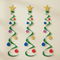 Three Christmas tree swirl decorations hanging against a softly lit wall