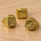Three gold-coloured rings close up on a wooden table, in square format