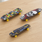 Three mini skateboards close up on a natural wood surface, in square format
