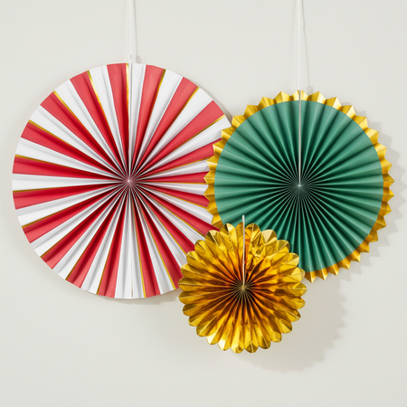 Three paper fan rosettes hanging against an off-white wall