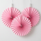 Three pink paper fans really close up against a white wall with soft light and shade, in square format