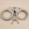 Tight square close-up of handcuffs folded inward on a wooden table with their keys