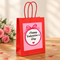 Valentine’s gift bag close up on a wooden table with soft lighting and subtle romantic touches, in square format