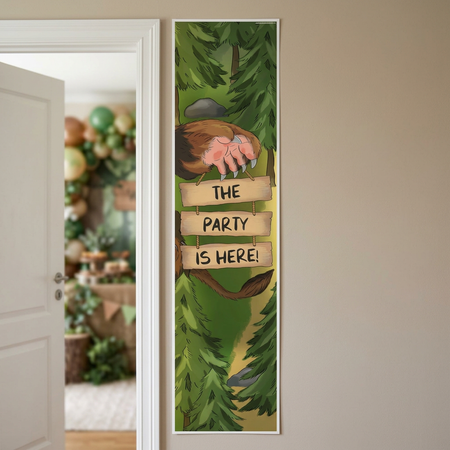 Woodland party banner on a neutral wall beside an open doorway into a woodland-themed party, close up in square format